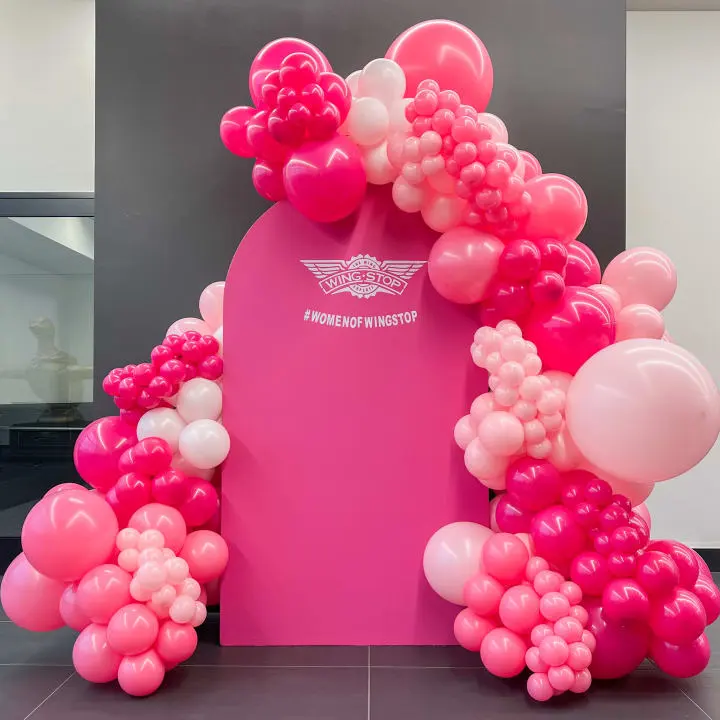 a bunch of balloons that are in the shape of a arch on a pink and gray floor in a room
