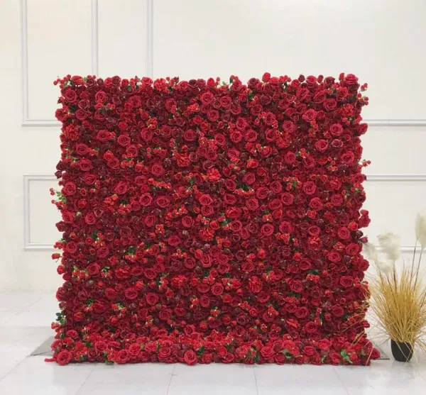 a large red flowered wall next to a potted plant in a room with a white wall behind it