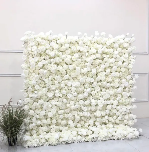 a large white flowered wall with a potted plant in front of it and a wall of white flowers behind it