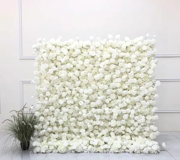 a white wall with white flowers and a potted plant in front of it on a tile floor next to a white wall