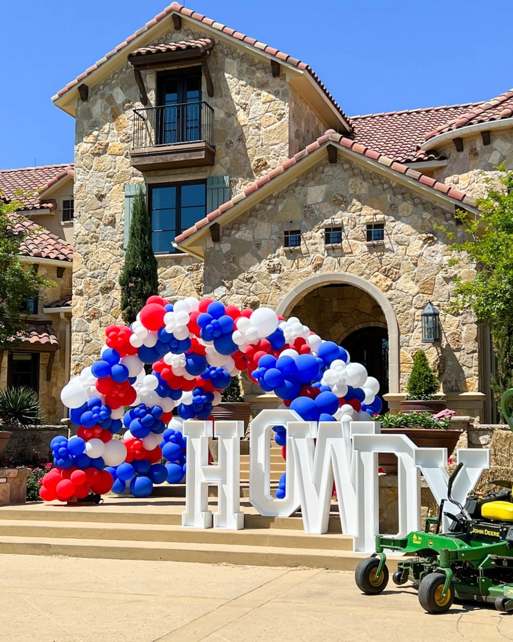 a lawn mower is parked in front of a house with balloons in the shape of the word love