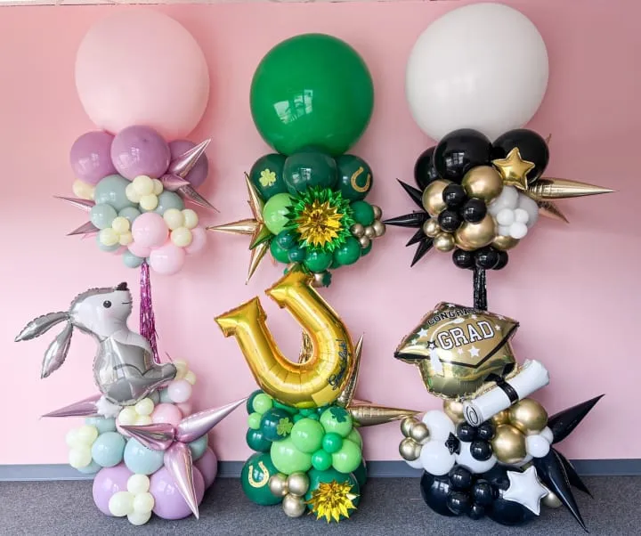 a group of balloons that are sitting on a floor next to a wall with a number of balloons on it