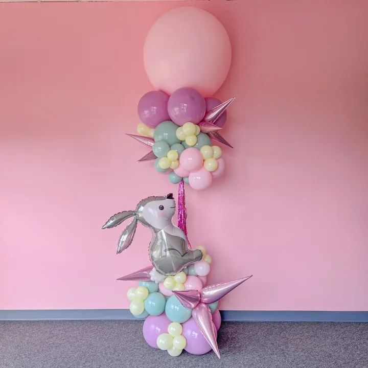 a stuffed animal sitting on top of a bunch of balloons in a room with a pink wall and floor