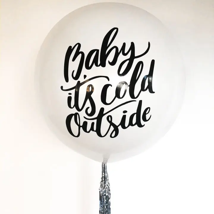 a white balloon with the words baby it's cold outside on it's side hanging from a string