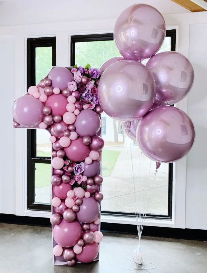 a large balloon column with a number one made out of pink and purple balloons in a room with a large window