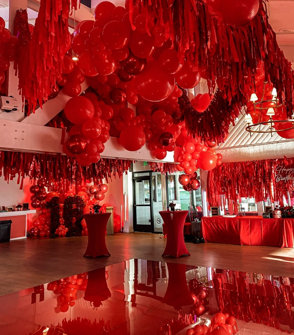 A large, open space filled with an abundance of vibrant red decorations, including hanging streamers, balloons, and other ornaments, creating a visually striking and festive atmosphere.