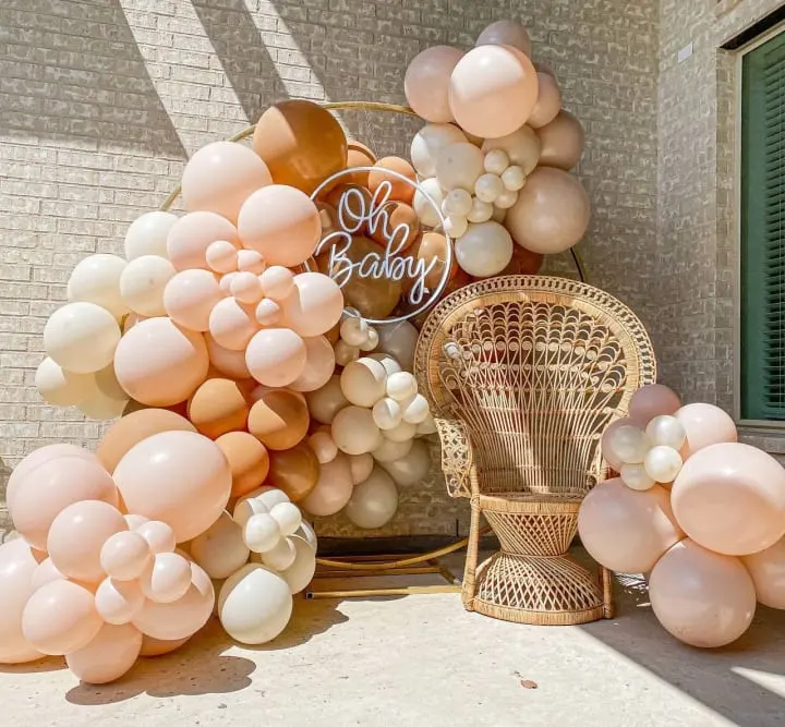 a bunch of balloons that are sitting on a chair in front of a building with a sign that says oh baby on it