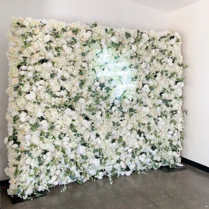 a wall of white flowers in a room with a white wall behind it and a white wall behind it