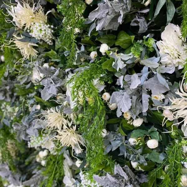 a close up of a green wall with white flowers and greenery on the top and bottom of it