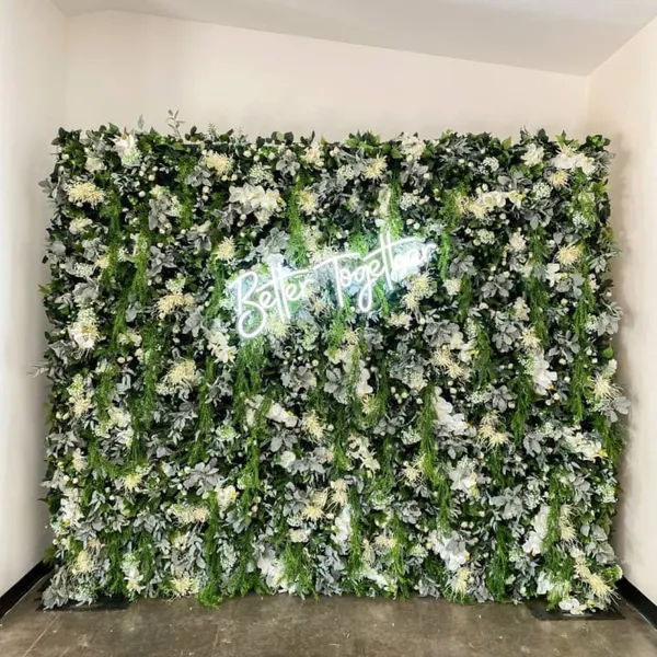 a green wall with white flowers and a neon sign that says be happy on the side of the wall