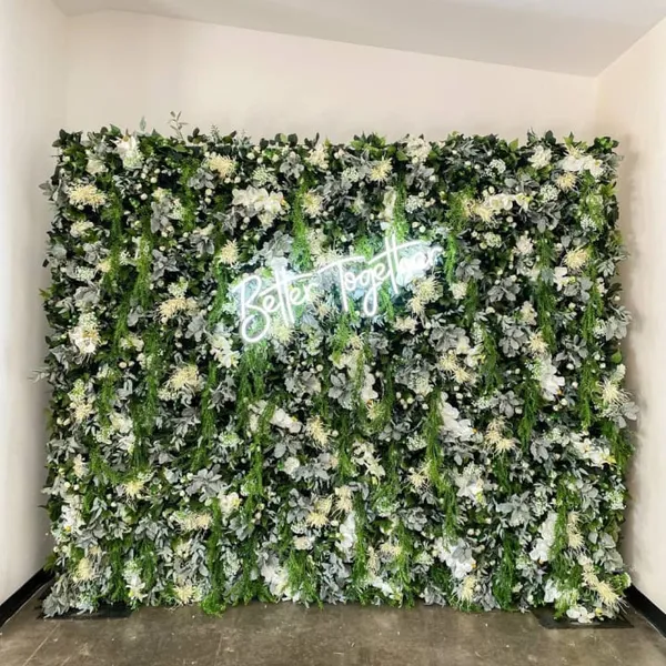a green wall with white flowers and a neon sign that says be happy on the side of the wall