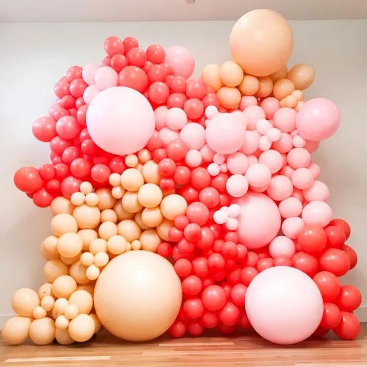 a large number of balloons floating in the air on a wooden floor in a room with a ceiling fan