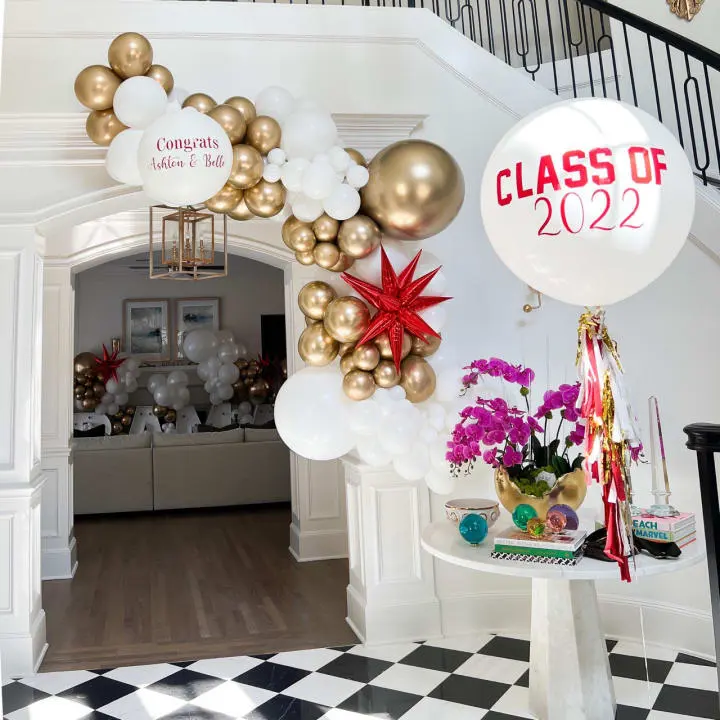 a balloon arch with a class of 2012 sign and balloons in the shape of a wreath on top of a table