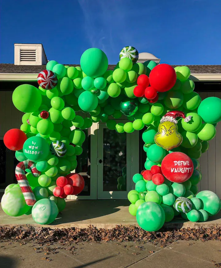 a large balloon arch in front of a house with a candy cane and candy canes on top of it