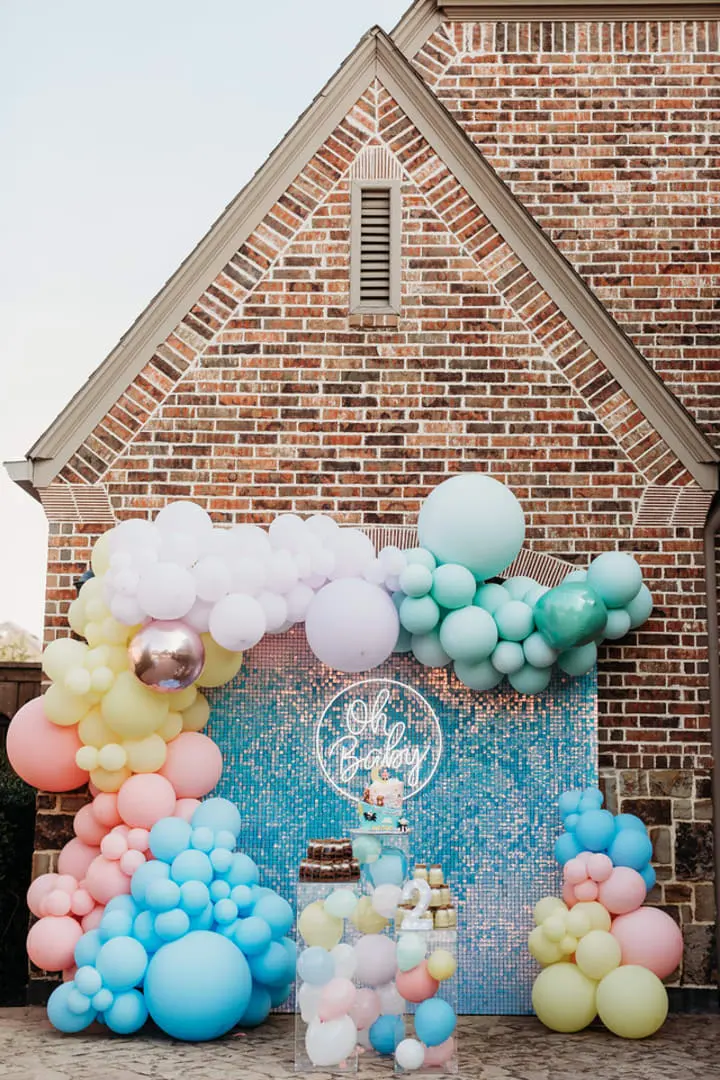 a bunch of balloons that are in front of a brick building with a clock on the side of the building