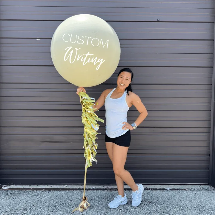 a woman holding a balloon that says custom writing on it and a string attached to the bottom of the balloon
