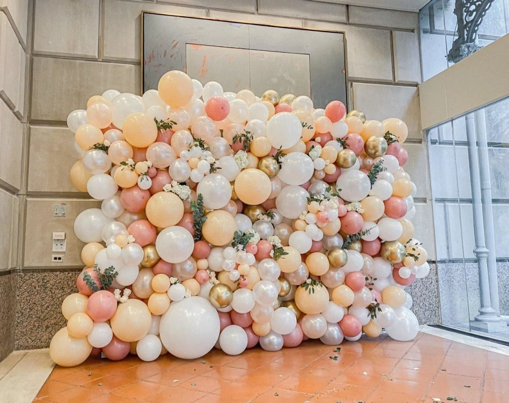 a bunch of balloons that are on the ground next to a wall with a door in the middle of it