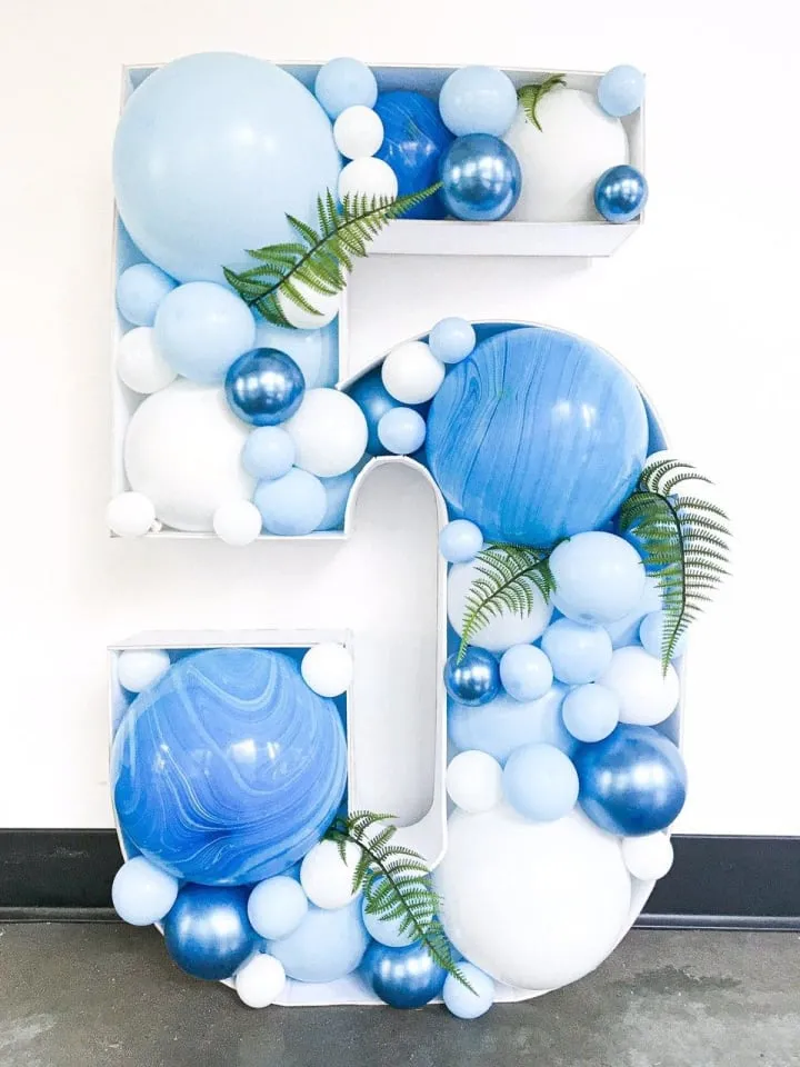 the letter e is made up of balloons and greenery in the shape of the letter e with a fern