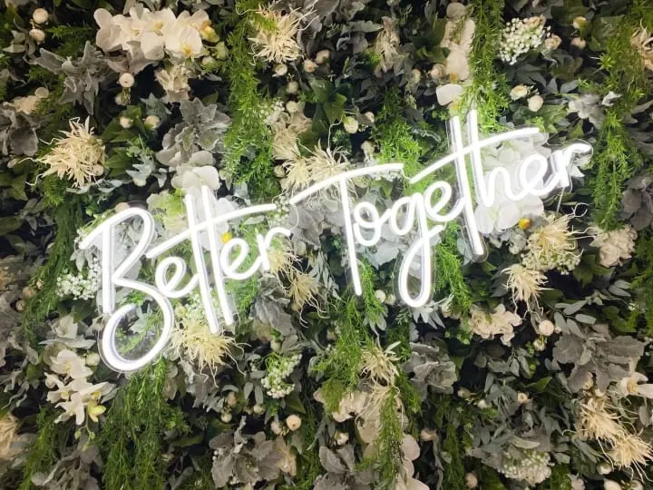 a wall of flowers with the words better together written in white letters on the top of the flower wall