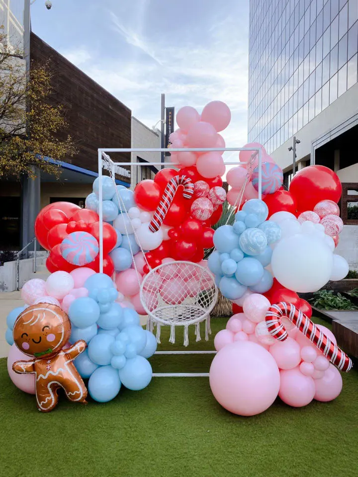 a bunch of balloons that are on the ground in front of a building with a teddy bear on it