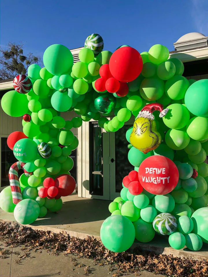 a bunch of balloons that are in the shape of a tree on a sidewalk in front of a building