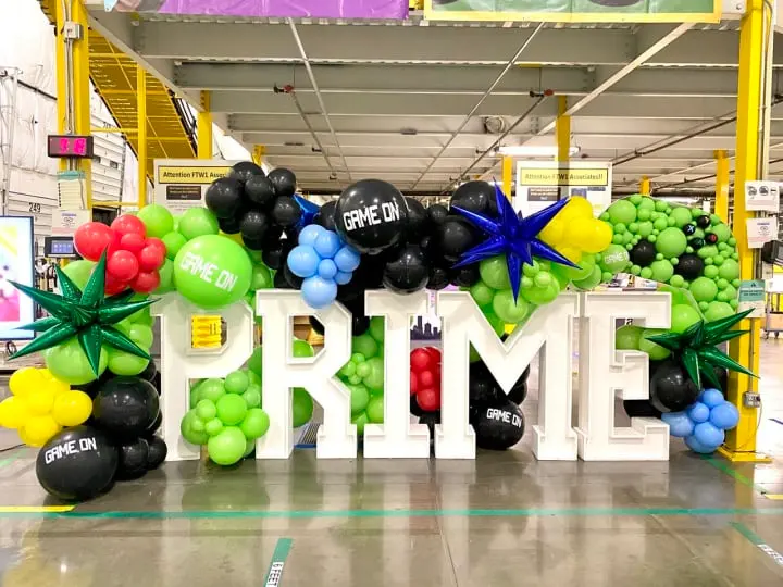 a large sign that says prime surrounded by balloons and a bunch of other balloons in a warehouse with a fire hydrant in the middle of the sign