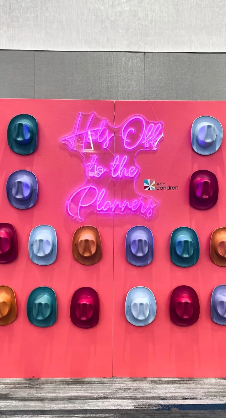 A vibrant red wall displays a neon sign that reads "It's all to the planets", surrounded by an array of colorful, spherical objects.